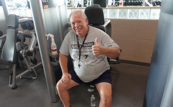 an older man sitting on a strength machine smiling and giving a thumbs up