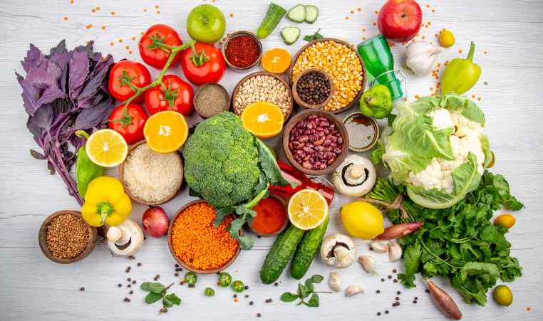 top view of fres foods, spices and vegetables on a white cooking table
